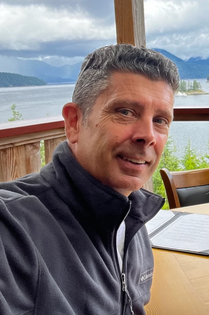 Steve, the owner of Canwest Construction sitting at a table with the ocean in the background